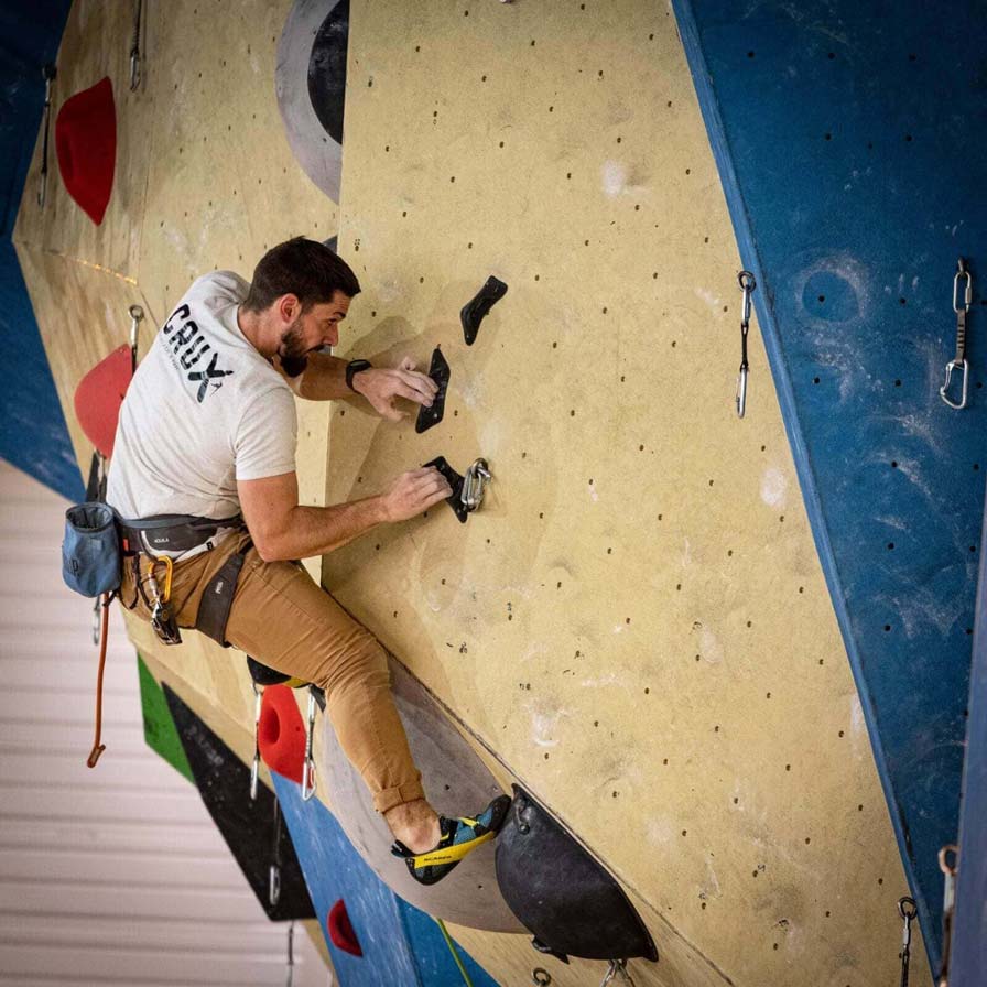 Kévin grimpe sur un mur d'escalade.